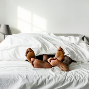 black couple laying in bed together focus on feet