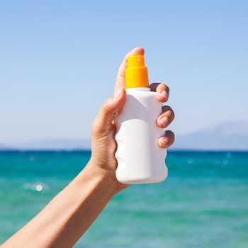 hand sunscreen bottle beach ocean water