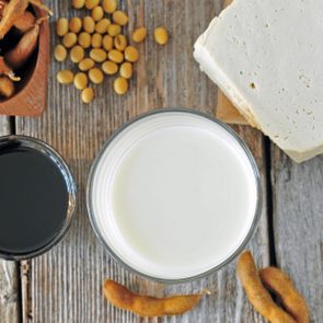 Glass of soy milk, soy sauce and soy tofu on a wooden table, top view. Soy food