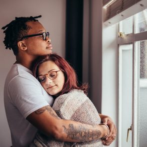 young couple hugging near window