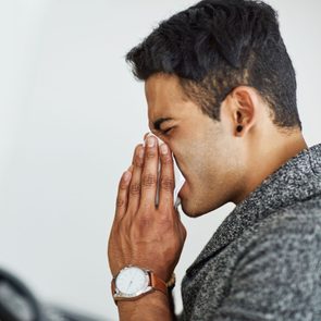 Man sneezing from the cover disease after getting vaccinated