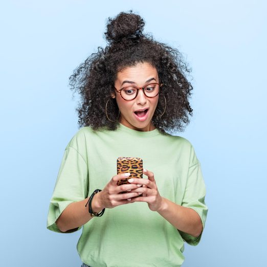 portrait of a surprised girl looking at her phone looking up statistics about How Many Sexual Partners Most Americans Have Had