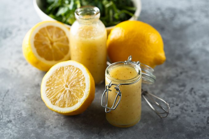 citrus Salad Dressing with lemons and salad in the background on gray surface